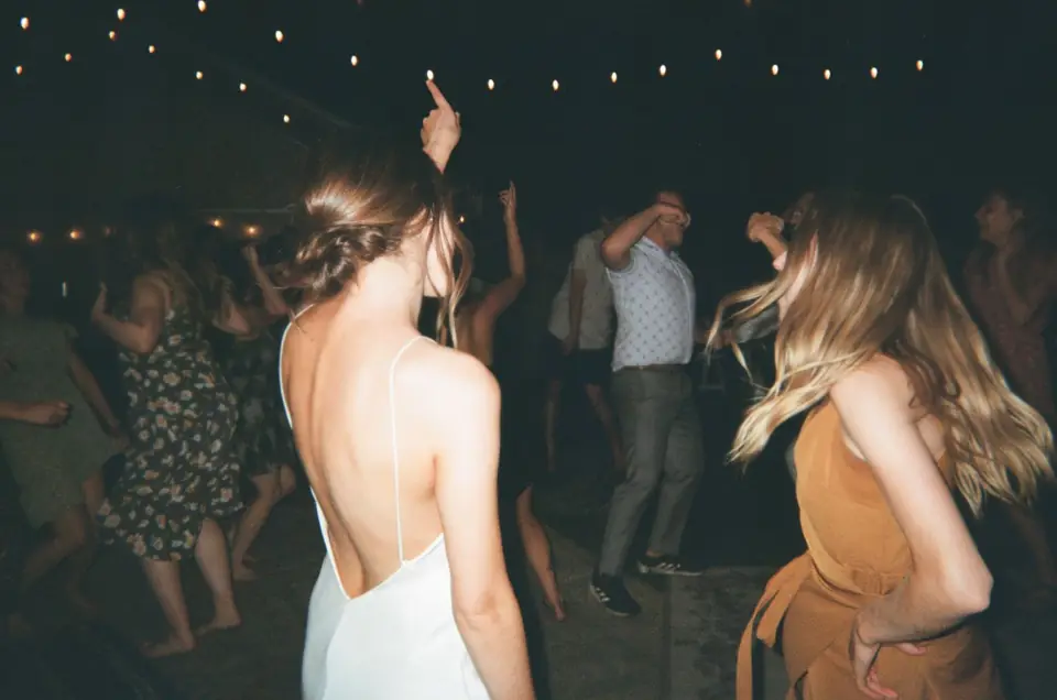 Guests dancing under string lights, hair flying
